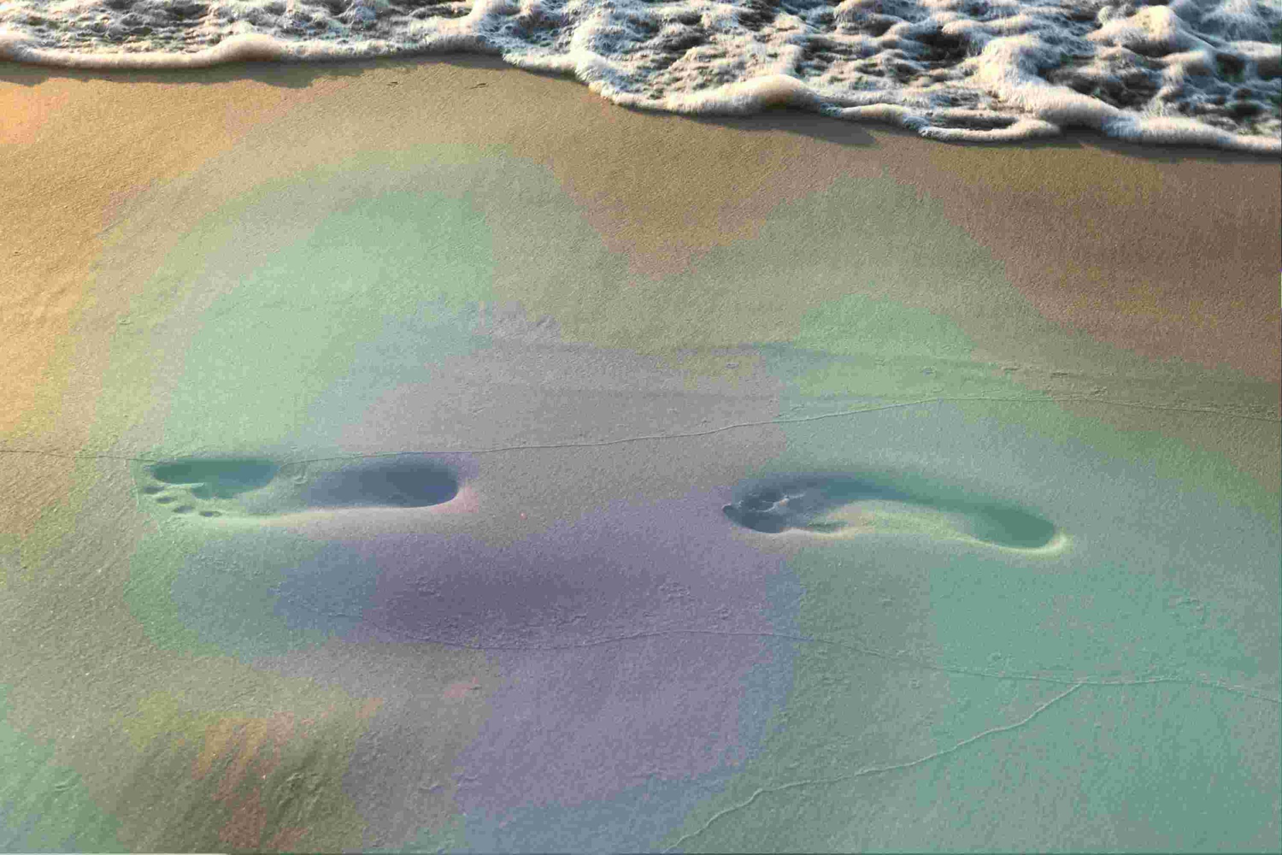 Fußabdrücke im Sand vor Wellen