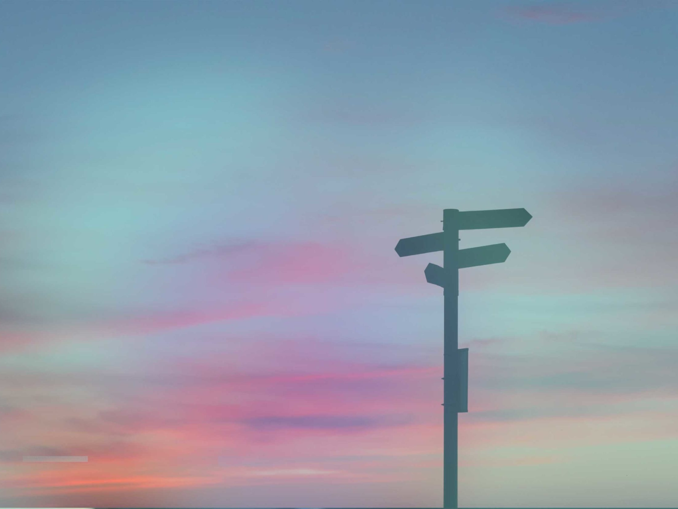 Hinweisschild mit vier Wegweisern im Sonnenuntergang